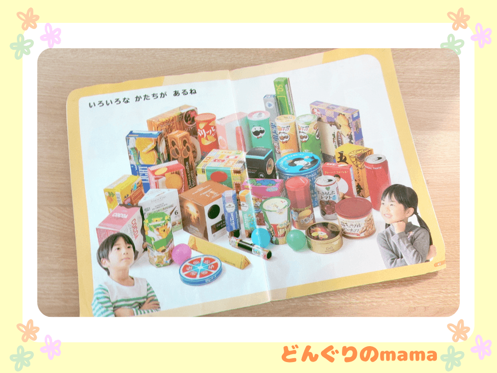 小学校1年生で使う空き箱の写真。算数の教科書の見開きページに、お菓子の空き箱を集めていろいろな形を学ぶ様子が写っている