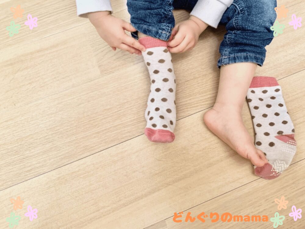 子どもが靴下を履いて外に出かける様子の足元アップ。公園や散歩など日常の外出シーンのイメージ。